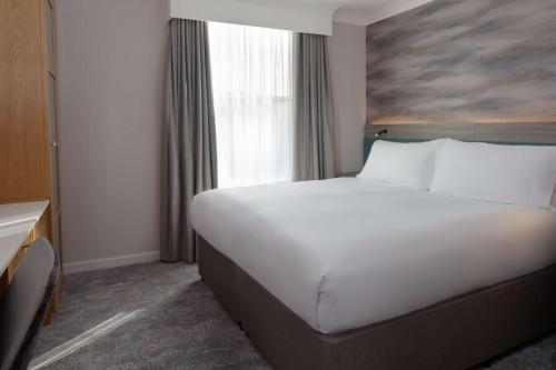 a large white bed in a hotel room with a window at DoubleTree by Hilton Bath in Bath