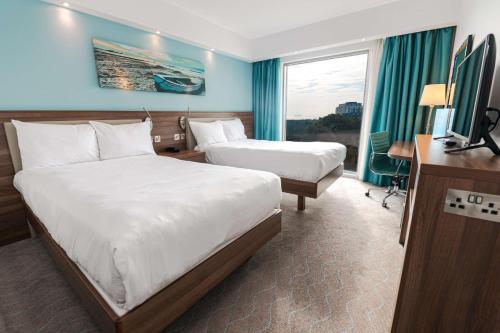 a hotel room with two beds and a television at Hampton by Hilton Bournemouth in Bournemouth