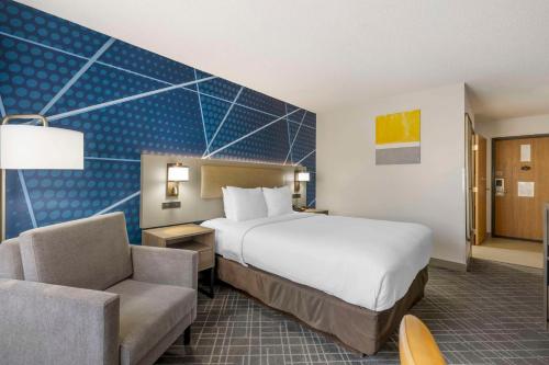 a hotel room with a large bed and a chair at Comfort Inn Hastings in Hastings