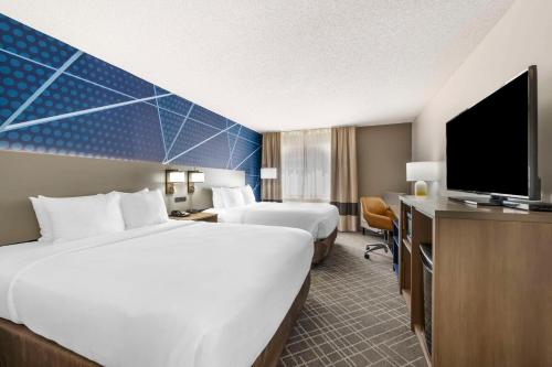 a hotel room with two beds and a flat screen tv at Comfort Inn Hastings in Hastings