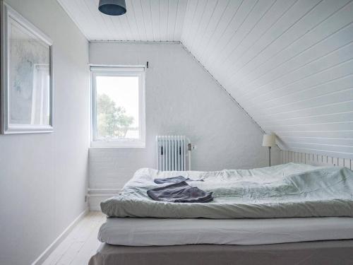 een bed in een witte kamer met een raam bij Holiday home Bindslev XVI in Bindslev