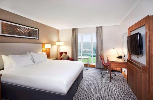 a hotel room with a bed and a desk and a tv at DoubleTree by Hilton Coventry in Coventry