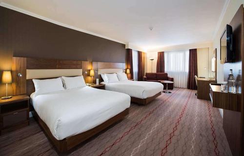 a hotel room with two beds and a chair at DoubleTree by Hilton Bristol North in Bristol