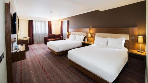 a hotel room with two beds and a chair at DoubleTree by Hilton Bristol North in Bristol