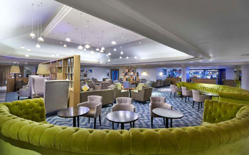 a hotel lobby with a yellow couch and tables and chairs at DoubleTree by Hilton Bristol North in Bristol