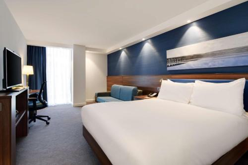 a hotel room with a large white bed and a desk at Hampton by Hilton Dundee City Centre in Dundee
