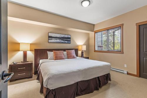 a bedroom with a large bed and a window at Spacious King Bed with Pool & Hot Tubs in Canmore