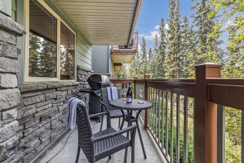 a patio with a table and chairs on a balcony at Spacious King Bed with Pool & Hot Tubs in Canmore