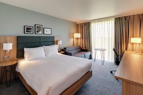 a hotel room with a large bed and a chair at Hilton Garden Inn Doncaster Racecourse in Doncaster