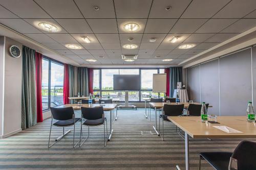 a conference room with tables and chairs and a screen at Holiday Inn Mulhouse by IHG in Mulhouse