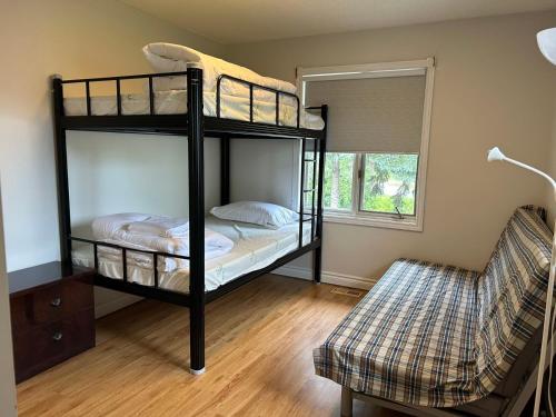 a bedroom with two bunk beds and a chair at Snug Harbour Cottage and Marina in Kawartha Lakes