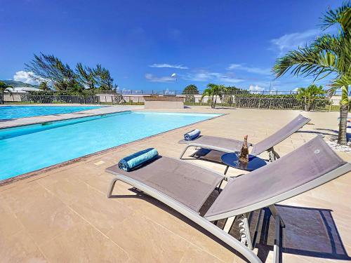 a swimming pool with two lounge chairs next to a swimming pool at Maison Caraibes beach front on Orient Bay with 2 big pools in Orient Bay