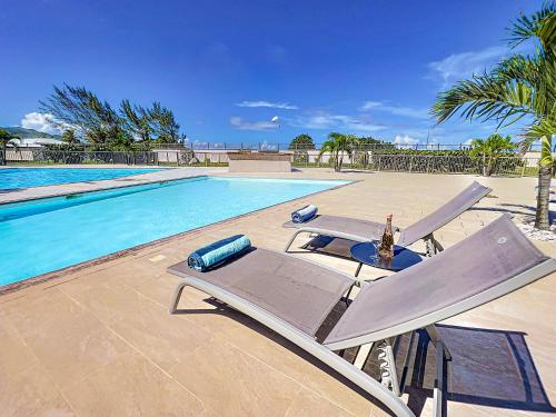 una piscina con due sedie a sdraio accanto a una piscina di Maison Caraibes beach front on Orient Bay with 2 big pools a Orient Bay