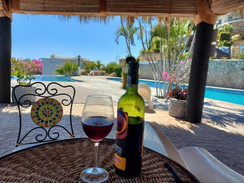 una botella de vino y una copa en una mesa en CasaBlancaGrand Colibrí en Acapulco