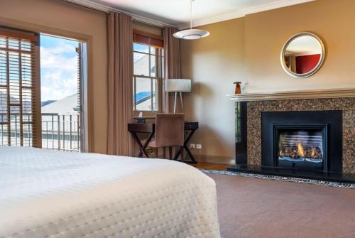 a bedroom with a fireplace and a bed and a desk at Tarraleah Estate in Tarraleah