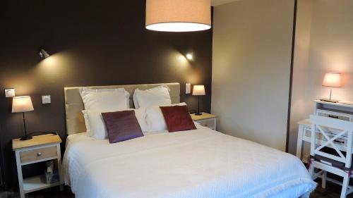 une chambre avec un grand lit blanc avec deux oreillers dans l'établissement Le Jardin Du Puits, à Longueville