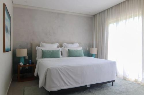 a bedroom with a large white bed with green pillows at île de Pipa - Ma Plage Hotel in Pipa
