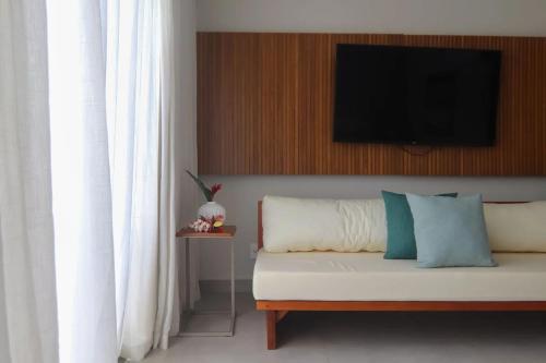 a bedroom with a couch with a television on a wall at île de Pipa - Ma Plage Hotel in Pipa
