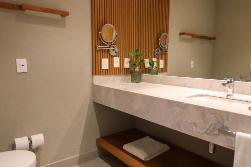 a bathroom with a sink and a toilet and a mirror at île de Pipa - Ma Plage Hotel in Pipa