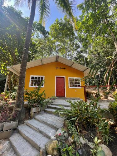 a yellow house with a red door in a forest at Hotel La Casablanca Tayrona in Calabazo