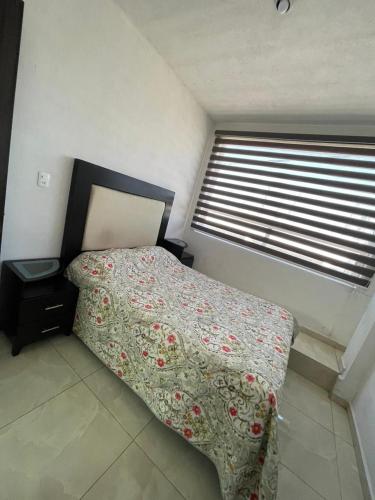 1 Schlafzimmer mit einem Bett mit Blumenbettdecke und einem Fenster in der Unterkunft Depa completo a 5 min del aeropuerto de Toluca in Toluca de Lerdo