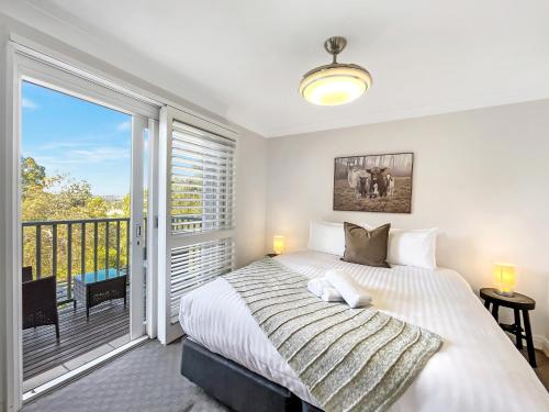 a bedroom with a large bed and a balcony at Villa AlaBet in Pokolbin