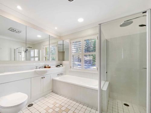 a bathroom with a tub and a toilet and a sink at Villa AlaBet in Pokolbin