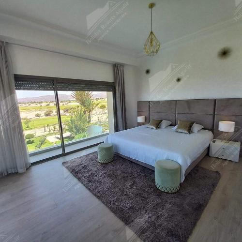 een slaapkamer met een groot bed en een groot raam bij Sea Breeze Villa Taghazout Bay Amda golf & ocean view in Tamraght Ouzdar