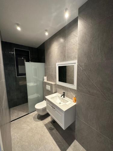 ein Badezimmer mit einem weißen Waschbecken und einem WC in der Unterkunft Pristina Select Apartments in Pristina