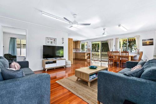 a living room with two blue couches and a tv at OceanViews on Burrum Whole in Burrum Heads
