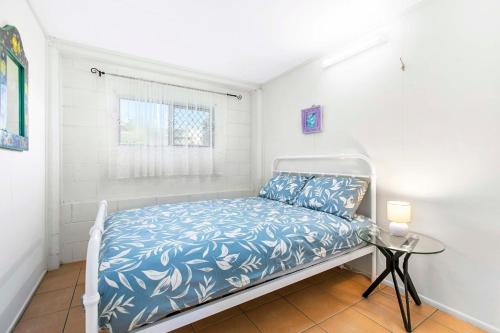 a white bedroom with a bed with blue and white sheets at OceanViews on Burrum Whole in Burrum Heads
