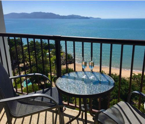 a table with two wine glasses on a balcony with the ocean at Beachfront Balcony in North Ward