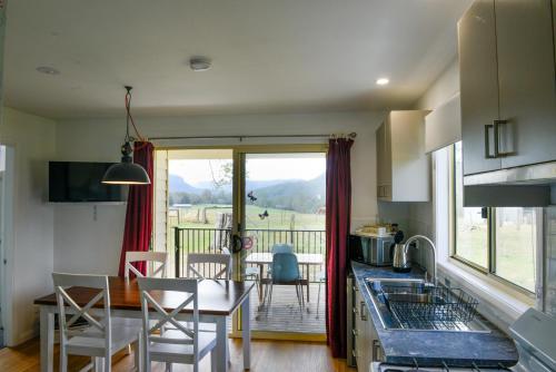 a kitchen and dining room with a view of a balcony at The Big Bell Farm in Kangaroo Valley