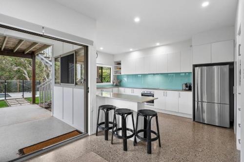 a kitchen with white cabinets and a counter with stools at 15 Wave Crescent in Marcoola