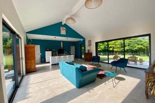 uma sala de estar com um sofá azul e cadeiras em Le Cottage proche du Golf em Panazol