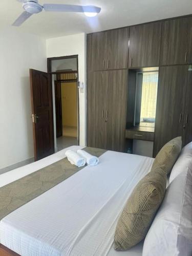 a bedroom with a large white bed with wooden cabinets at Grey Pearl Apartments Where Raha is Also Our Priority in Malindi