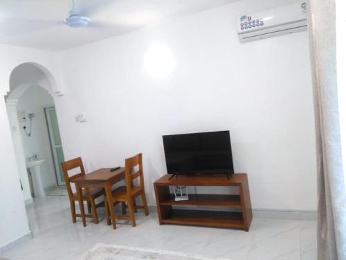 - un salon avec une télévision, une table et des chaises dans l'établissement Grey Pearl Apartments Where Raha is Also Our Priority, à Malindi