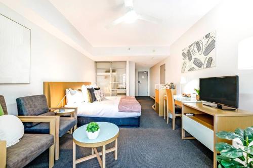 a hotel room with a bed and a tv at Metropolis Mirage - A Poolside CBD Studio in Darwin