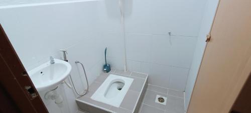 a white bathroom with a toilet and a sink at ADIMA Homestay in Kuala Terengganu