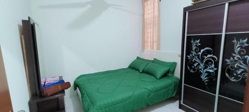 a bedroom with a green bed and a cabinet at ADIMA Homestay in Kuala Terengganu