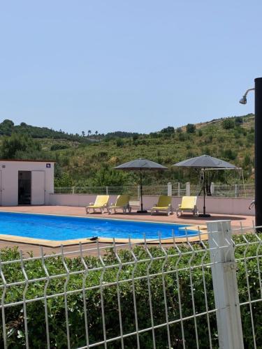 a swimming pool with chairs and umbrellas on a building at Quinta das Covas - Trancoso in Trancoso