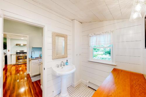 baño blanco con lavabo y ventana en Come About Cottage, en Wareham