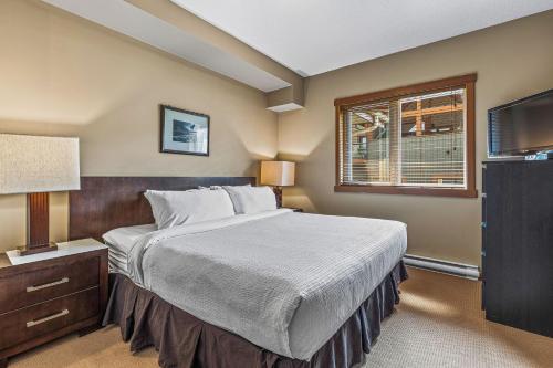 Un dormitorio con una cama grande y un televisor. en King Bed - Top Floor Grizzly, en Canmore