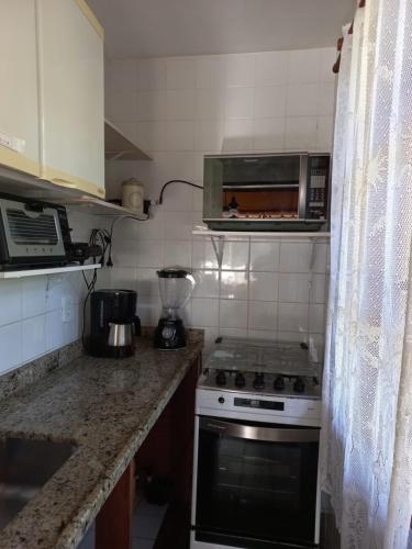 a kitchen with a stove and a microwave at Casa com churrasqueira piscina privativa em São Pedro da Serra - Perto de Lumiar in Nova Friburgo