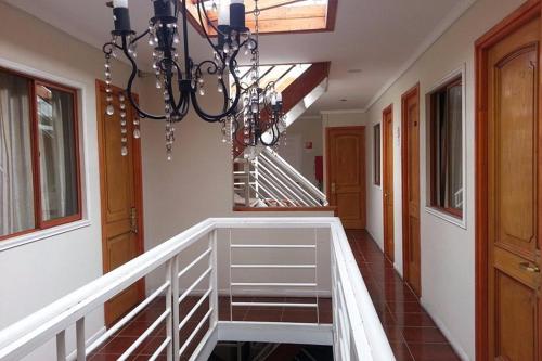 un couloir avec un escalier et un lustre dans l'établissement Andina Hostel, à Iquique
