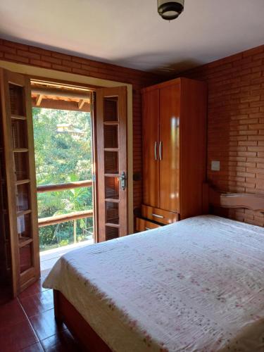 a bedroom with a large bed and a large window at Casa com churrasqueira piscina privativa em São Pedro da Serra - Perto de Lumiar in Nova Friburgo