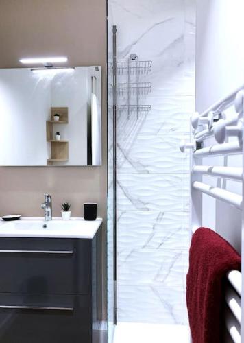 La salle de bains est pourvue d'un lavabo et d'une porte de douche en verre. dans l'établissement La Vila Joiosa, à Saint-Herblain