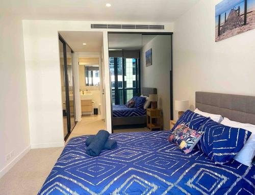 a bedroom with a bed with a blue comforter and a mirror at So Unique! Collins Street Vibe 2B2B in Melbourne