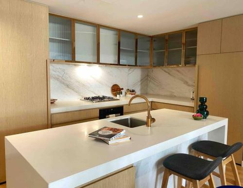 a kitchen with a sink and a counter with two chairs at So Unique! Collins Street Vibe 2B2B in Melbourne