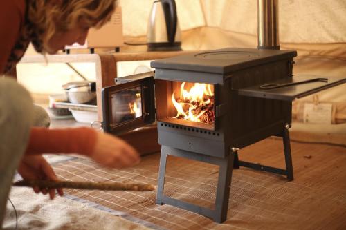 a person is pulling a stick in a stove at Colorado Glamping in Montevideo
